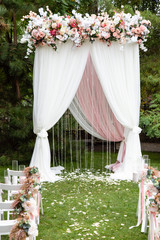 Fototapeta na wymiar Wedding ceremony arch outdoors at park with flowers