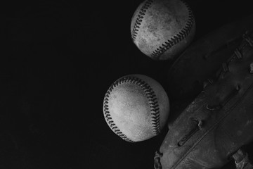 Baseballs on black background and copy space.  Close up view from above of old grunge balls and glove.