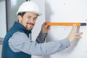 male builder measuring a wall