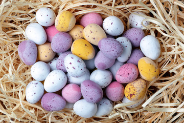 A cluth of Easter candy eggs on a straw background