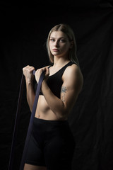 Portrait of a girl in a fitness gym close-up against a dark background.
