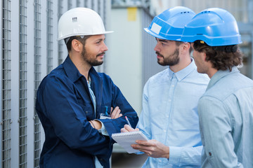 three engineers checking plans with documents at construction site