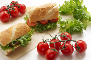 sandwiches with tomatoes, lettuce and cheese on a light background, next to cherry, selective focus