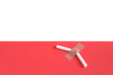 A broken cigarette on a light pink background, symbolizing the harm of smoking.
