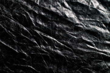 Wrinkled artificial fabric. Black background with white curves.