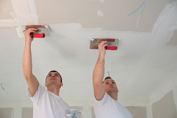 Two construction workers doing a hard finish of a ceiling