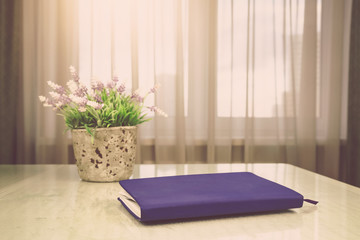 purple notebook lies on white table near pink and green lavender pot plant against window