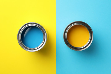 Cans of blue and yellow paint on two tone background, top view