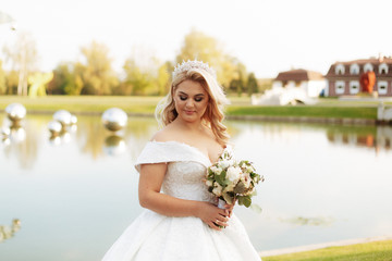 Young beautiful woman with long hair and blue eyes in long fabulous wedding dress in autumn park. Fairytale princess in the fall wood.