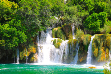 A picturesque cascade waterfall among large stones in the Krka National Landscape Park, Croatia in spring or summer. The beautiful Croatian waterfalls, mountains and nature.