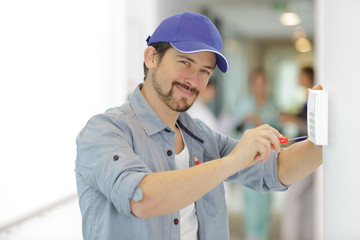 happy male worker fixing a thermostat in hospital