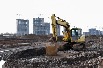 Yellow excavator with bucket at building under construction. Backhoe at large scale construction...