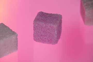 Bright sugar cubes on the pink background