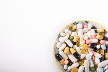 Pills on a white plate. A pile of multi-colored tablets disguised as food on a plate with cutlery. Medicines on a white plate.