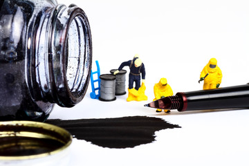 Conceptual image of miniature figure people wearing hazmat suits inspecting a fountain pen and spilled ink