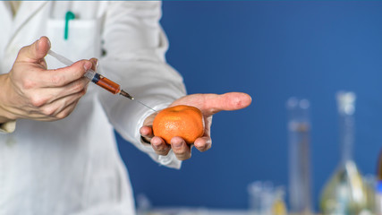 laboratory assistant injects into a orange citrus with nitrates so that they are fresh, GMOs.