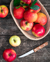 red and yellow apples in a basket on a wooden background