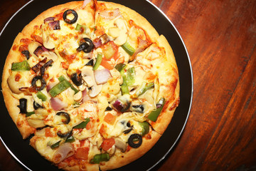 pizza in a black tray, wood table background