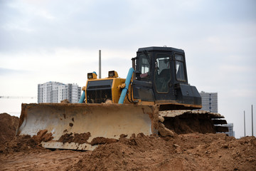 Bulldozer during land clearing and foundation digging at large construction site.  Crawler tractor with bucket for pool excavation and utility trenching. Dozer, Earth-moving equipment.