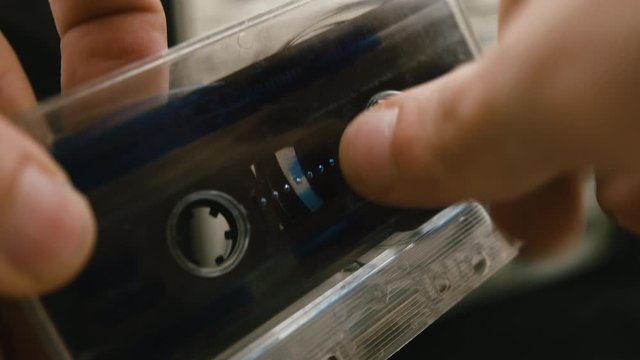 With a cassette and a pen in hand, it rewinds it forward or back. Concept of old music listening.