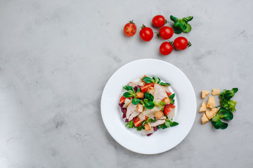 Fresh Caesar salad with delicious chicken breast, spinach, cabbage, arugula, Parmesan and cherry tomatoes on a light background. Caesar sauce, lemon, broken cheese. The concept of healthy and dietary 