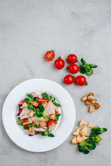 Fresh Caesar salad with delicious chicken breast, spinach, cabbage, arugula, Parmesan and cherry tomatoes on a light background. Caesar sauce, lemon, broken cheese. The concept of healthy and dietary 