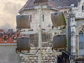 Metal pole with large spotlights. Rear view, against the background of an ancient building and the walls of the fortress.
