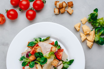 Fresh Caesar salad with delicious chicken breast, spinach, cabbage, arugula, Parmesan and cherry tomatoes on a light background. Caesar sauce, lemon, broken cheese. The concept of healthy and dietary 