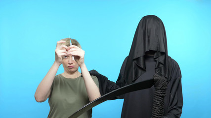 scene. blue background. the woman shows the syringe of death goes