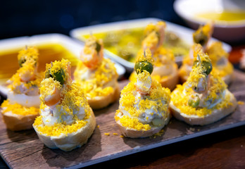 Appetizing spanish tapas with salad and grated egg yolk on a wooden tray in San Sebastian, Donostia, Spain