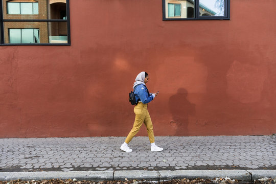 Young woman walking along sidewalk