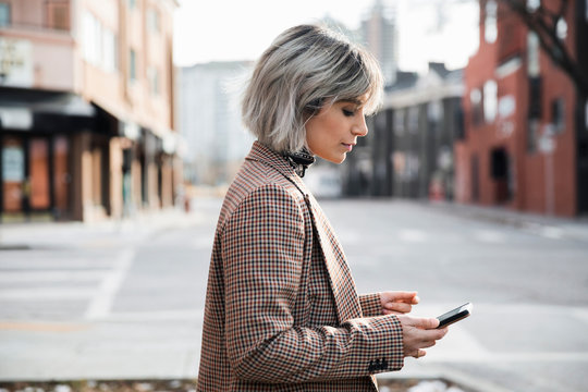 Woman using smart phone on urban sidewalk