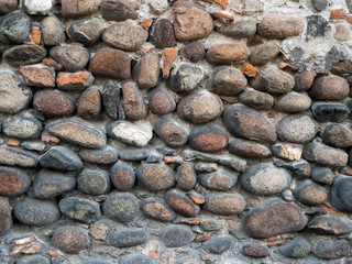 Wall of large cobblestones. The stones are closely pressed together and cemented. Stone background.