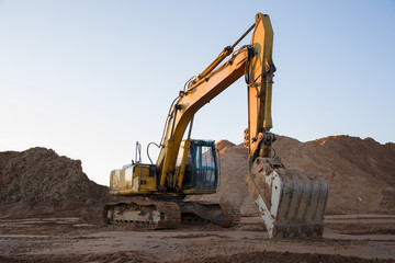 Track-type excavator during earthmoving work at open-pit mining. Loader machine with bucket in sand quarry. Backhoe digging the ground for the foundation and for laying sewer pipes district heating