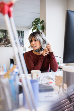 Businesswoman talking on telephone at office desk
