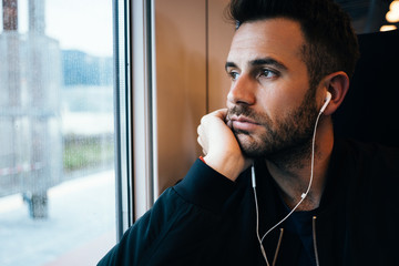 Young man traveling by train wearing earphones