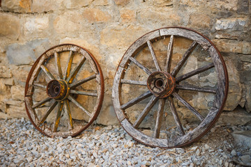 Fototapeta na wymiar Old wooden cart wheels. Vintage wheels from a horse drawn cart are leaning against a stone wall