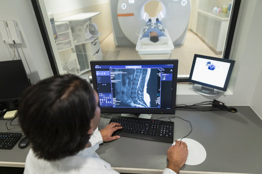 Radiology Technologist Operating MRI Machine In Computer Room