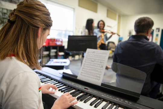 Junior high girl student playing electric piano in classroom