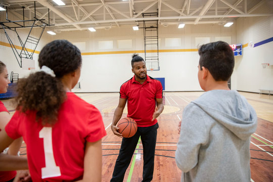 Junior high basketball coach coaching students in gym