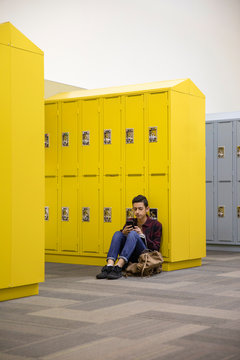 Junior high using smart phone at lockers in corridor