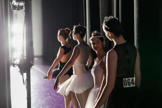 Young female ballerina waiting and talking with friend off stage