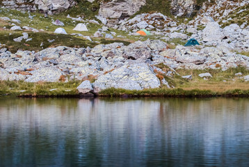 Camping with tents near mountain lake. Amazing mountain campsite among the rocks and stones. Hiking in the Carpathians.