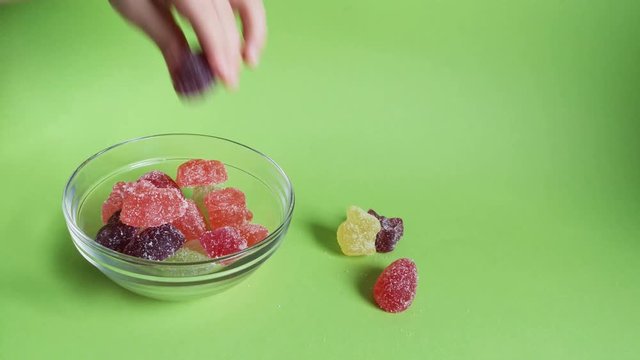 Child's hand takes marmalade from bowl,green backdrop.Easter treats for children