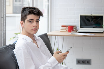 teenager or male student with mobile phone at home on the couch