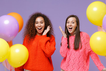 Excited two european african american women friends in knitted sweaters isolated on violet purple...