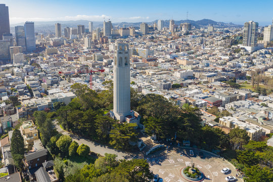 Aerial daytime view of Coit Tower, San Francisco, California, USA. Tower is in center of photos with downtown San Francisco buildings in background.