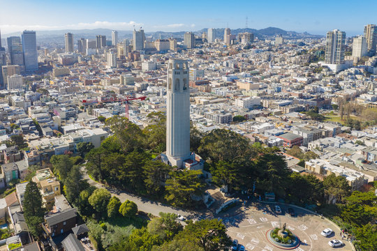Aerial daytime view of Coit Tower, San Francisco, California, USA. Tower is in center of photos with downtown San Francisco buildings in background.