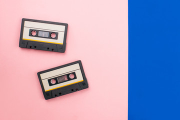 Two retro audio cassettes flat lay on colorful blue and pink background top view with copy space. Creative design in minimal 80-s style. Music, radio, dj concept. Web banner template. Stock photo.
