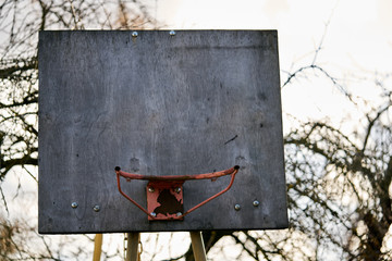 rusty old basketball hoop against a sky in the evening.